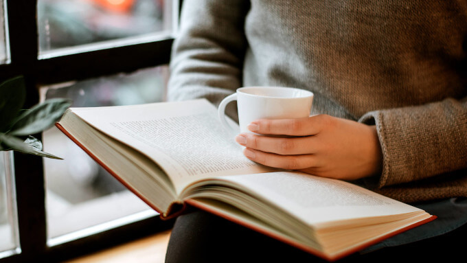カップを片手に本を読む人
